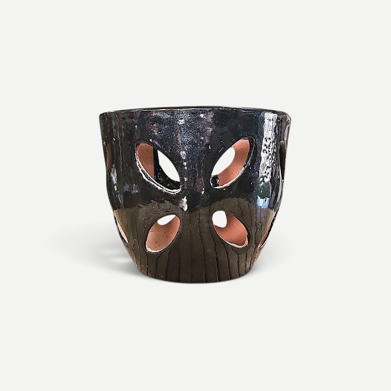 Hawaiian Discovery Furniture Malu orchid pot featuring a dark glazed exterior with decorative cutouts and terracotta base