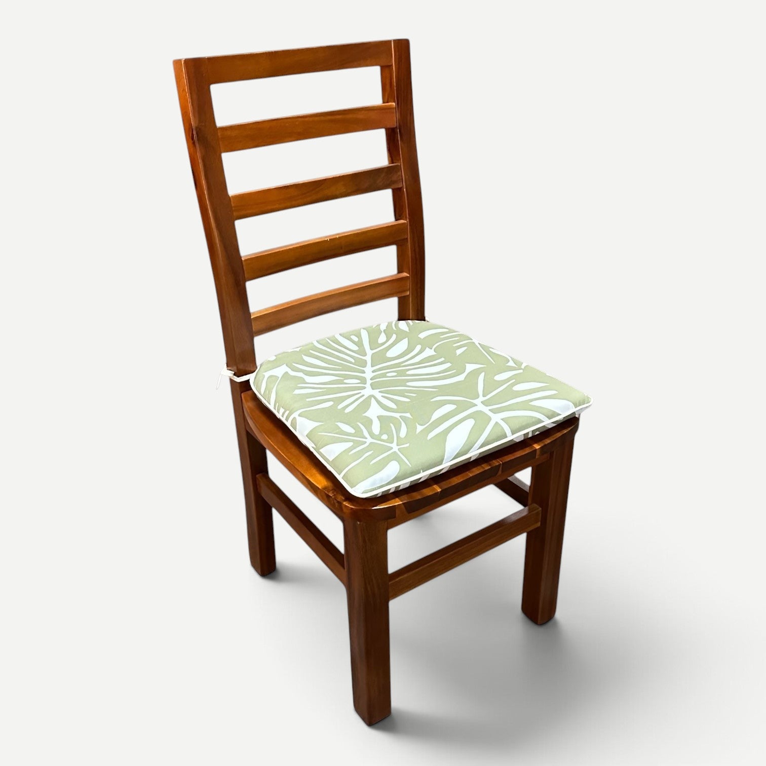 Hawaiian Discovery Furniture chair pad with green and white tropical monstera leaf pattern on a wooden dining chair