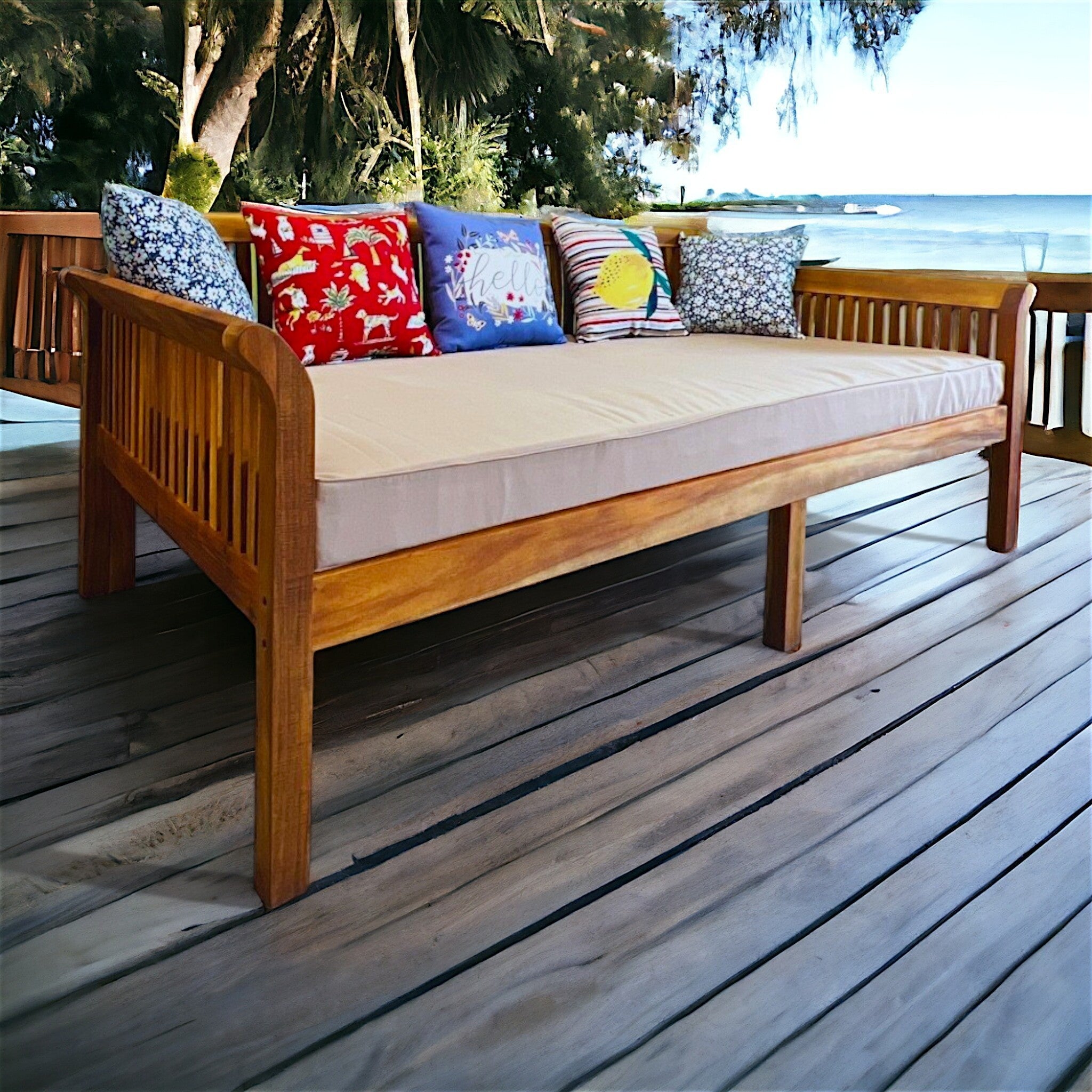 Hawaiian Discovery Furniture Riviera Daybed made of acacia wood with a taupe twin cushion on a wooden deck