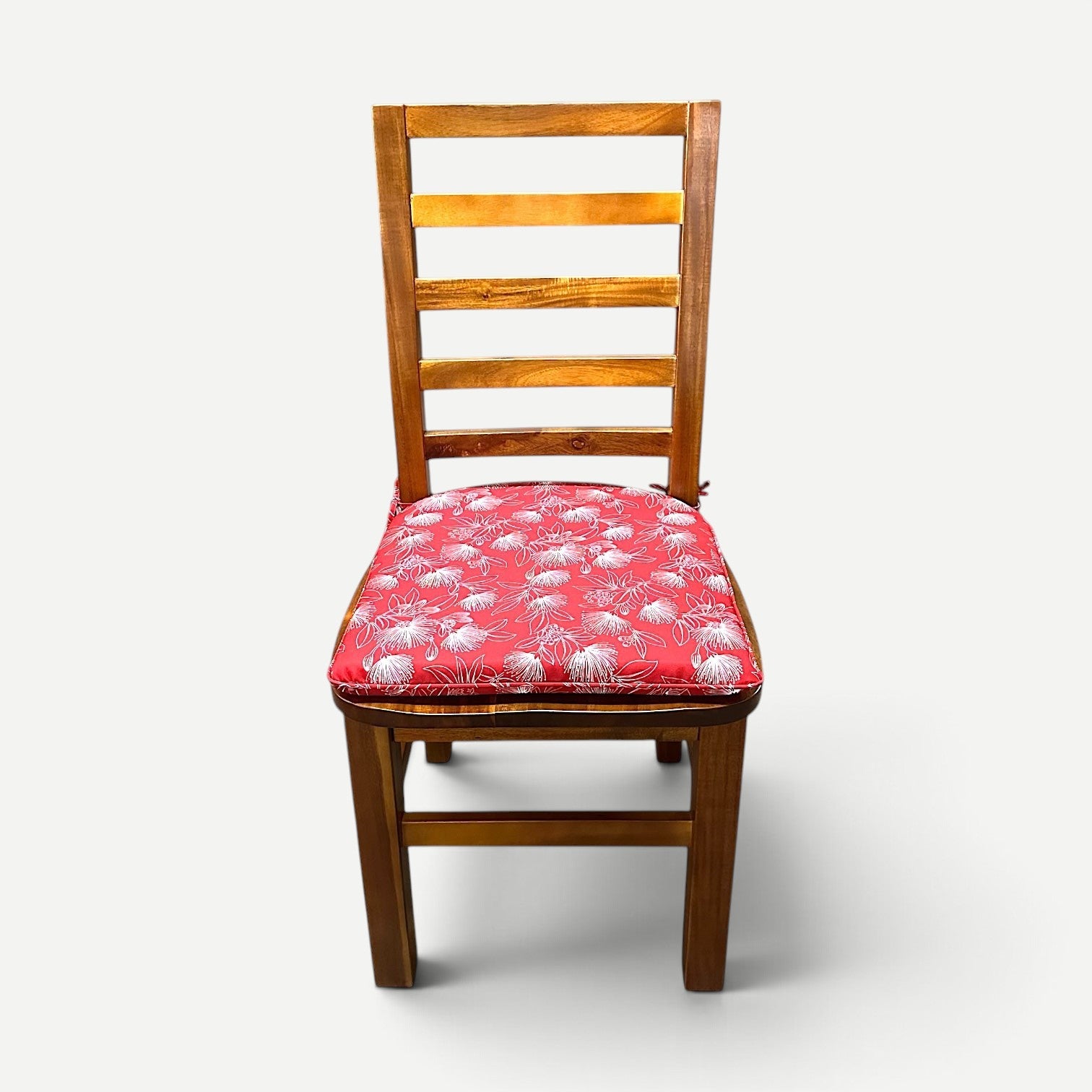 Hawaiian Discovery Furniture chair pad with red and white floral pattern on a wooden dining chair