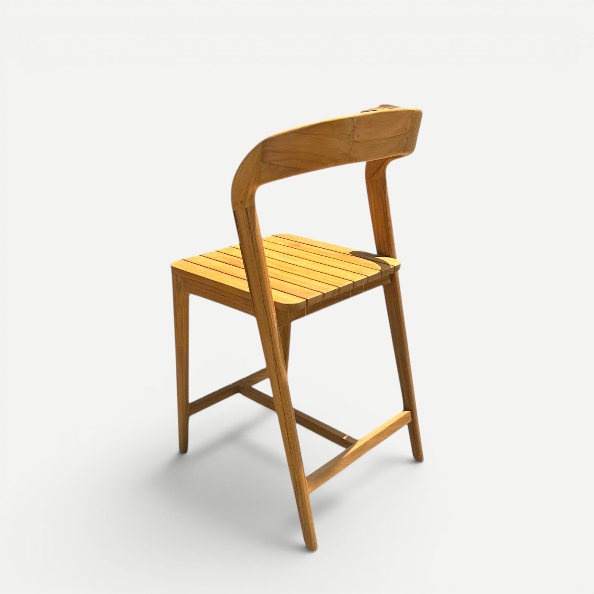 Hawaiian Discovery Furniture Noho teak counter stool with a slatted seat and curved backrest in a natural wood finish.