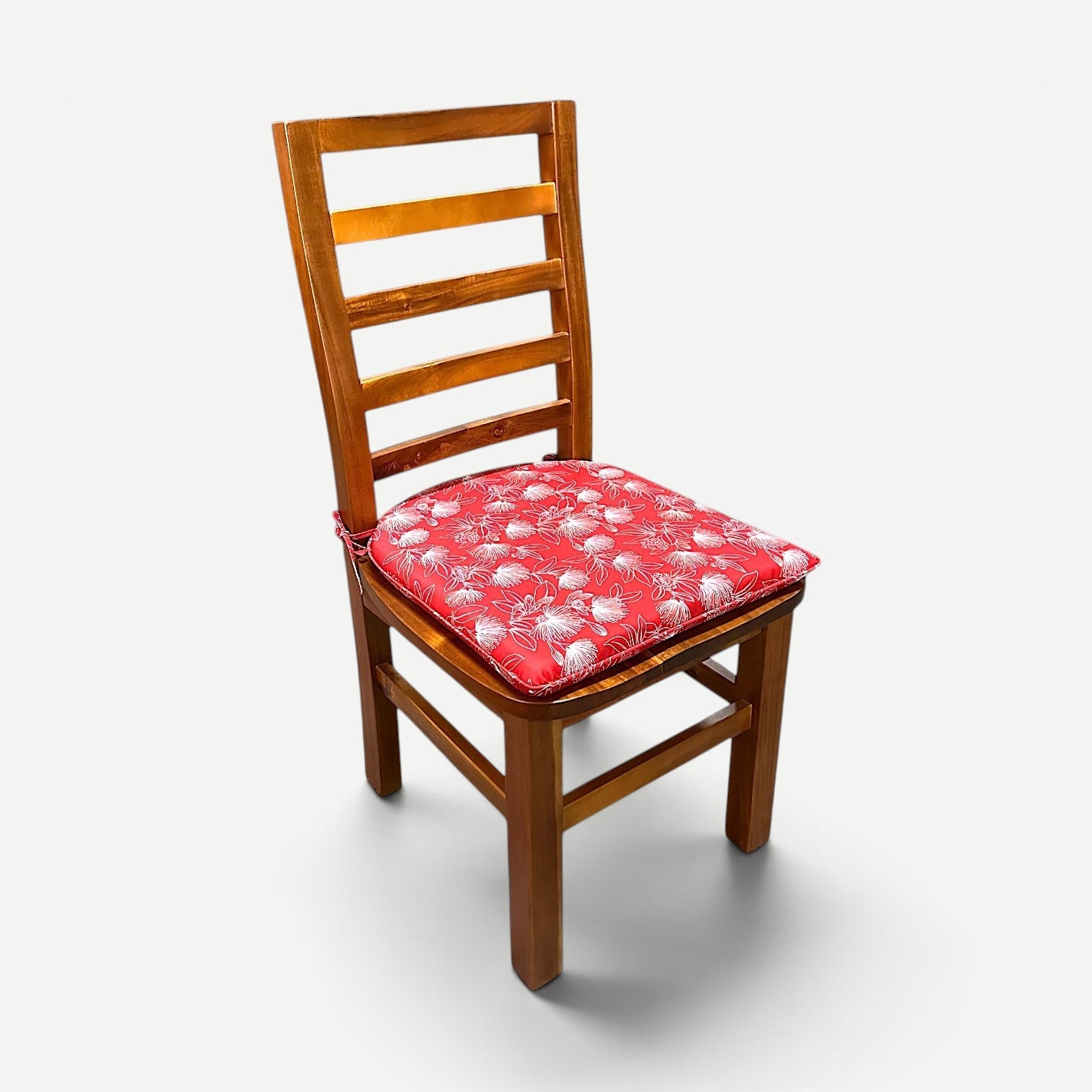 Hawaiian Discovery Furniture red polyester chair pad with white floral pattern on a wooden Haleiwa dining chair
