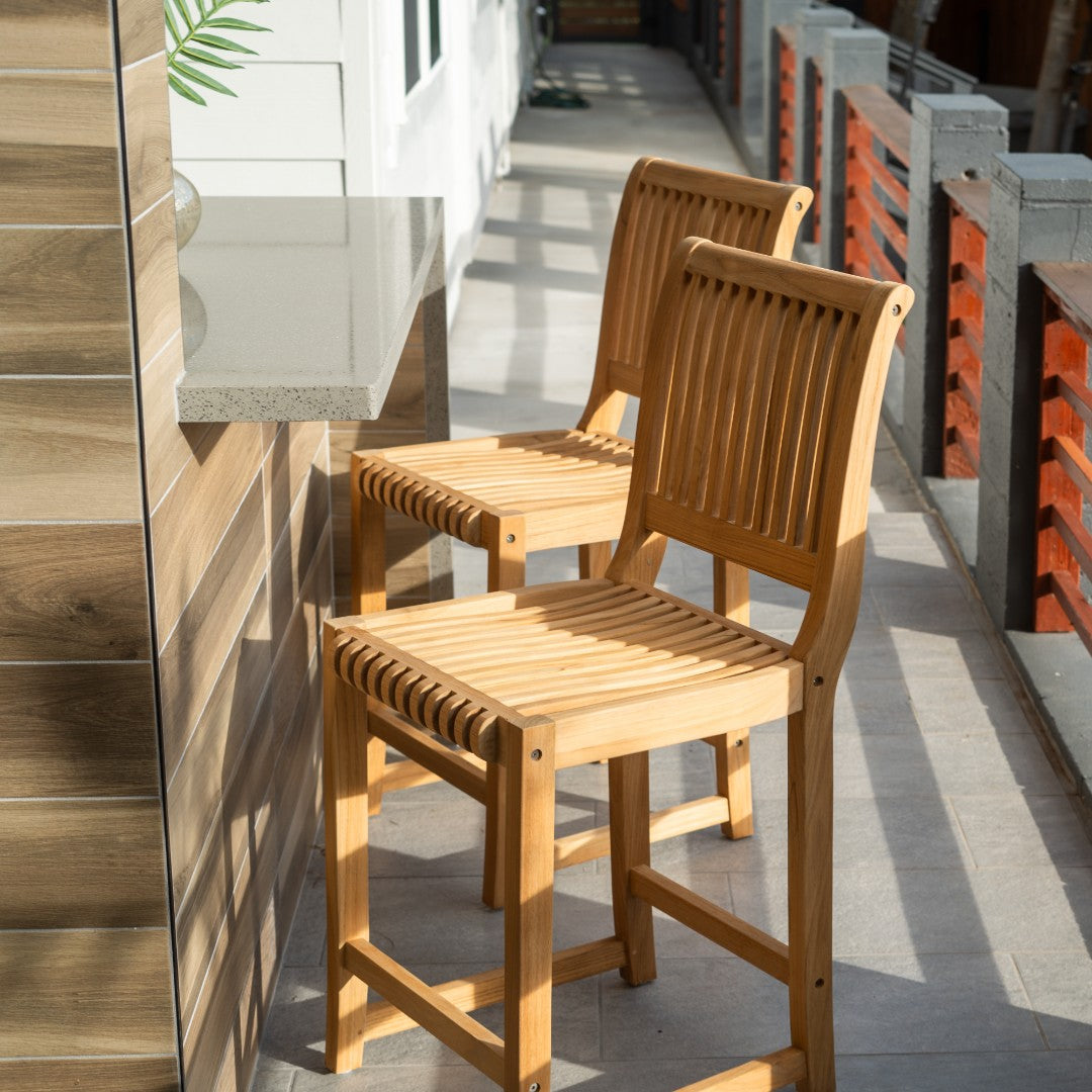 Hawaiian Discovery Furniture Palm High Teak Bar Chairs with slatted back and seat on a sunny outdoor patio.