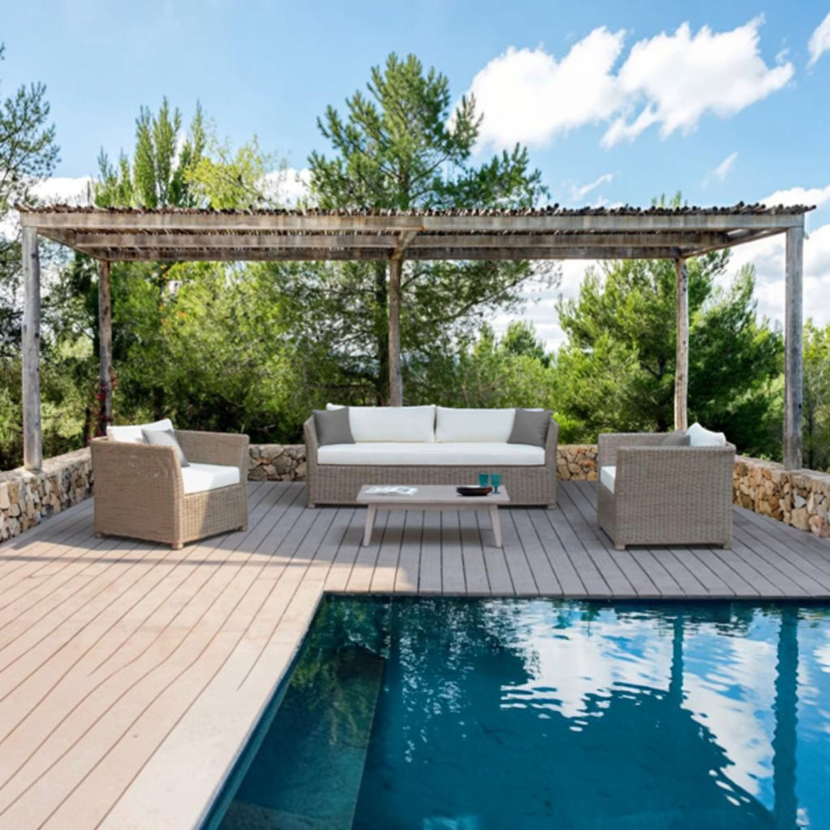 Hawaiian Discovery Furniture Wailele teak coffee table centered in a wicker patio set by a poolside deck