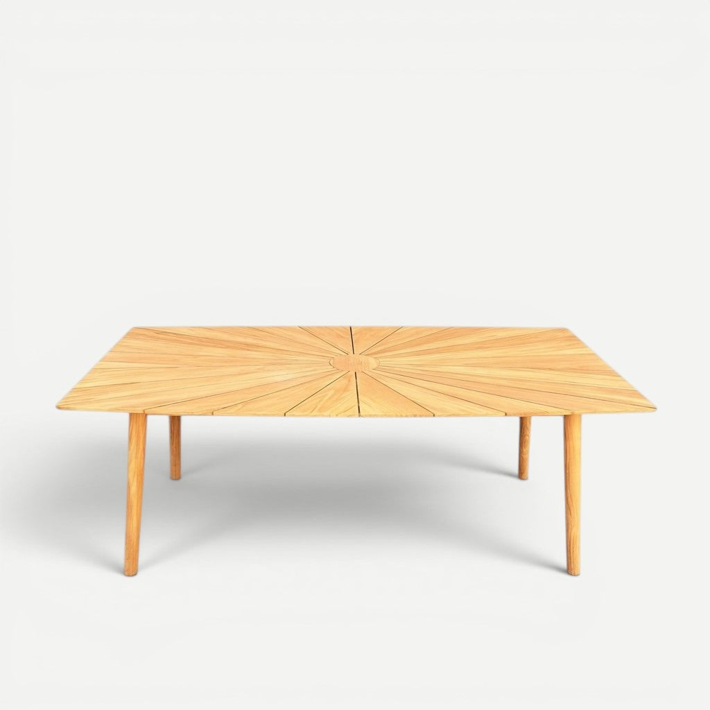 Hawaiian Discovery Furniture Cambria solid teak outdoor dining table with a sunburst pattern top and tapered legs.