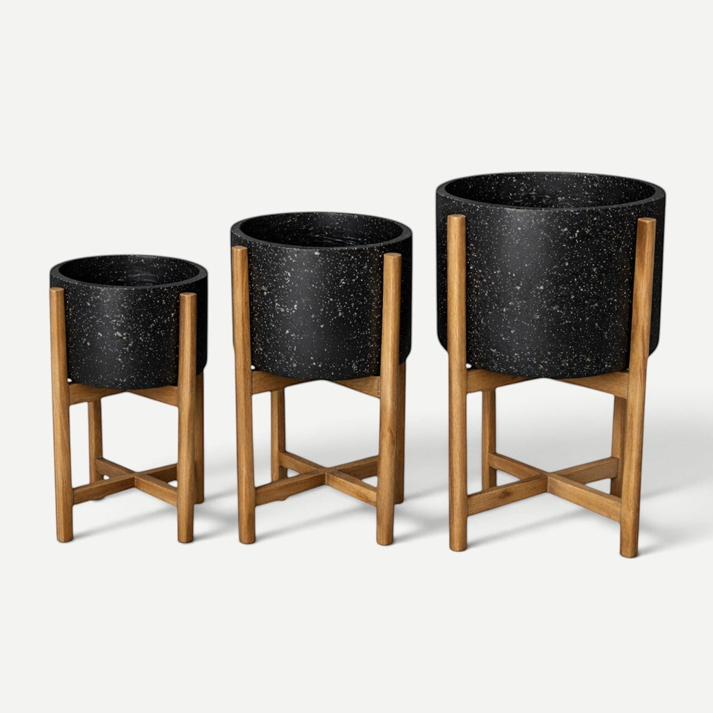 Hawaiian Discovery Furniture terrazzo planters in black with acacia wood stands in three different sizes.