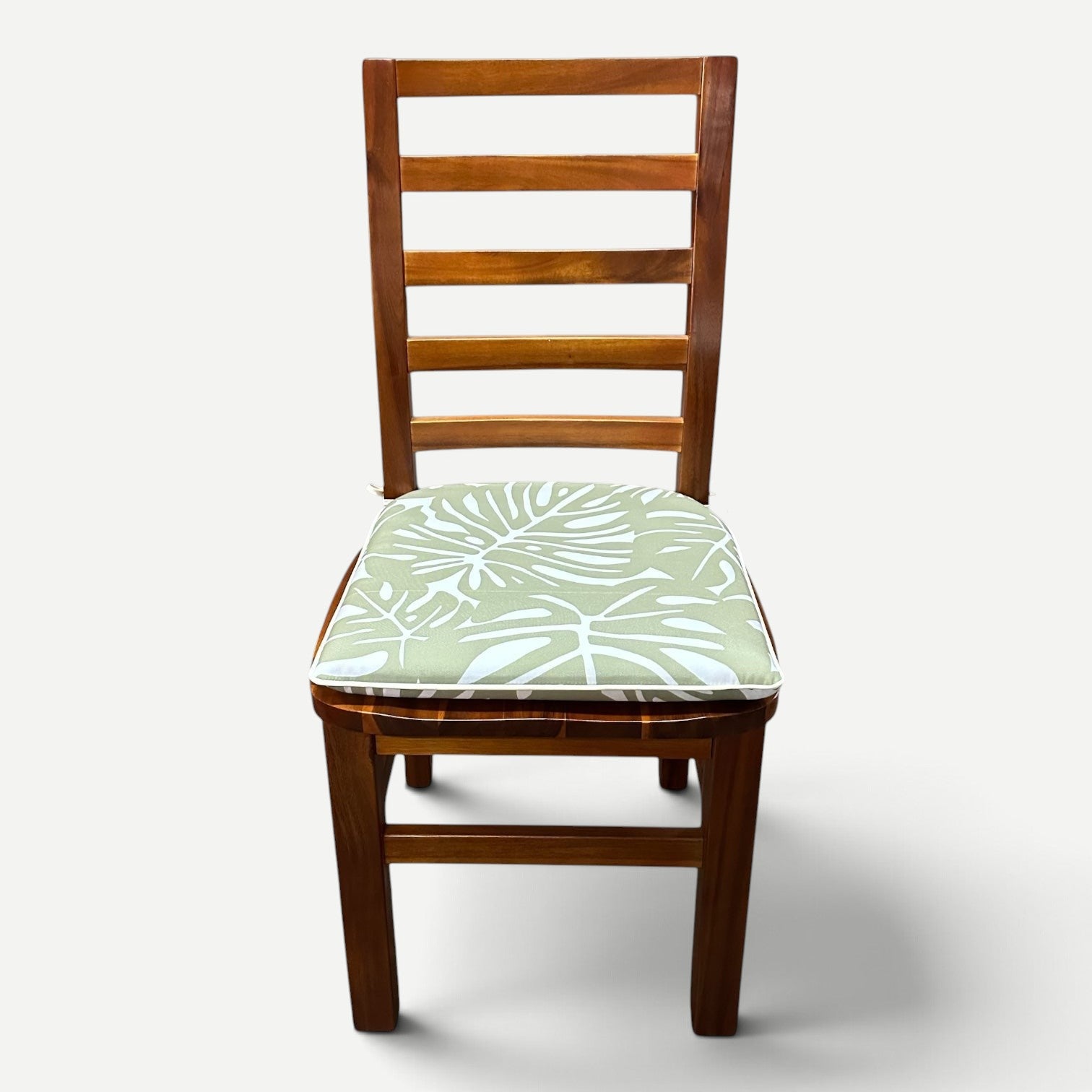 Hawaiian Discovery Furniture chair pad with green and white tropical leaf pattern on a wooden dining chair